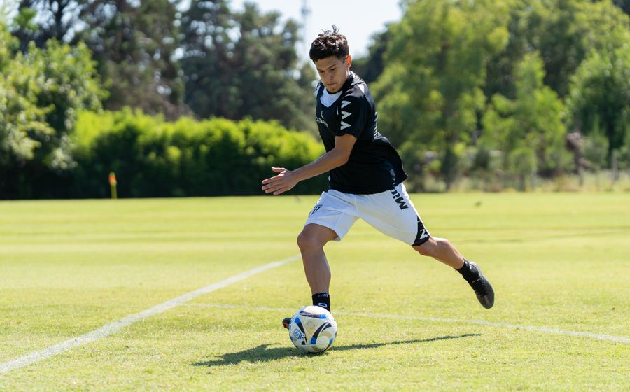 A teenage footballer training on a sunny pitch