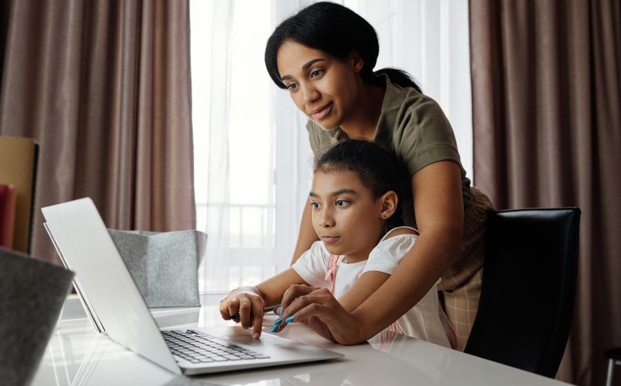 A parent supporting her daughter with an online lesson at home